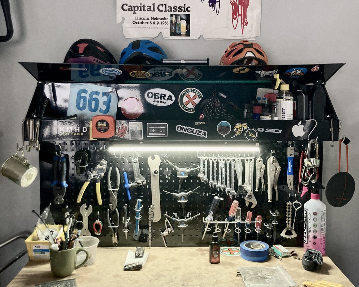 Bike shop, workbench Workbench in a home bike shope with magnetic pegboard, thick with a motley assortment of tools. The workbench is covered with bicycle and outdoor sports-related stickers