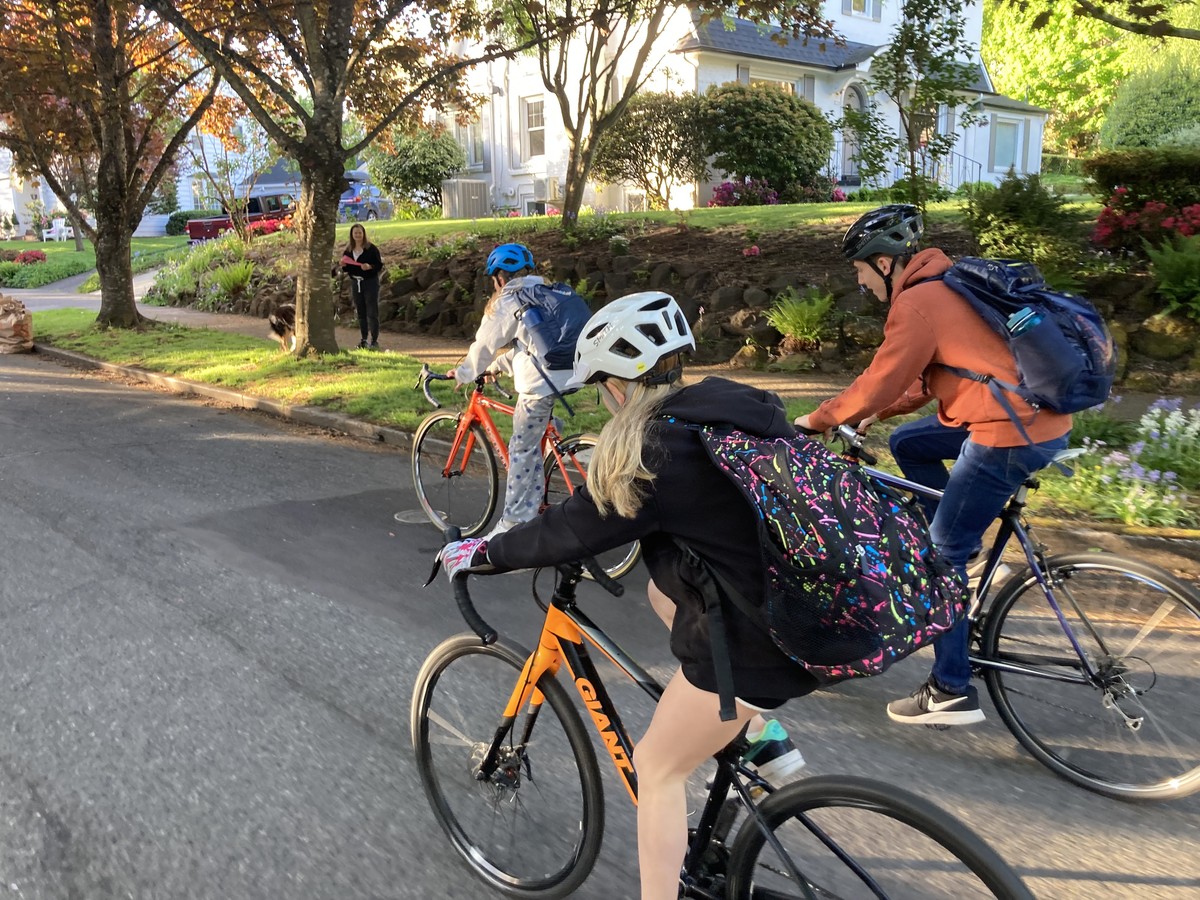 Three tween/teenage kids on bikes, with backpacks