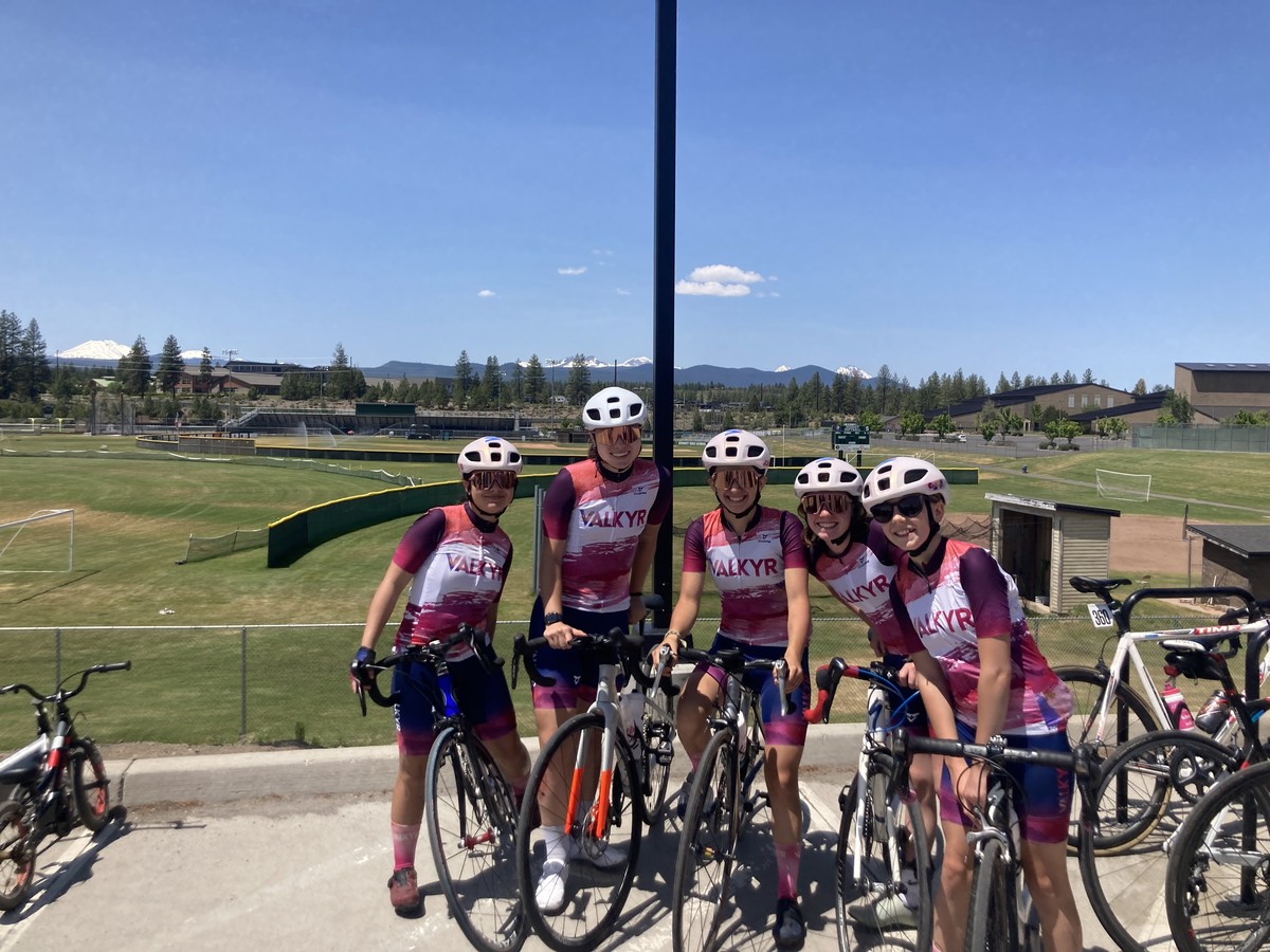 VALKYR juniors in kit after Sunday ride VALKYR juniors in kit after Sunday ride, with bikes, at the edge of a field. Mt. Bachelor and the Sisters, snowy, are peeking over a forested ridgeline on the horizon