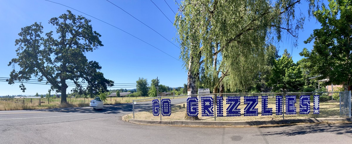 Go Grizzlies Panorama of the front of a school on Scholls Ferry Road, with “GO GRIZZLIES” woven into a chainlink fence